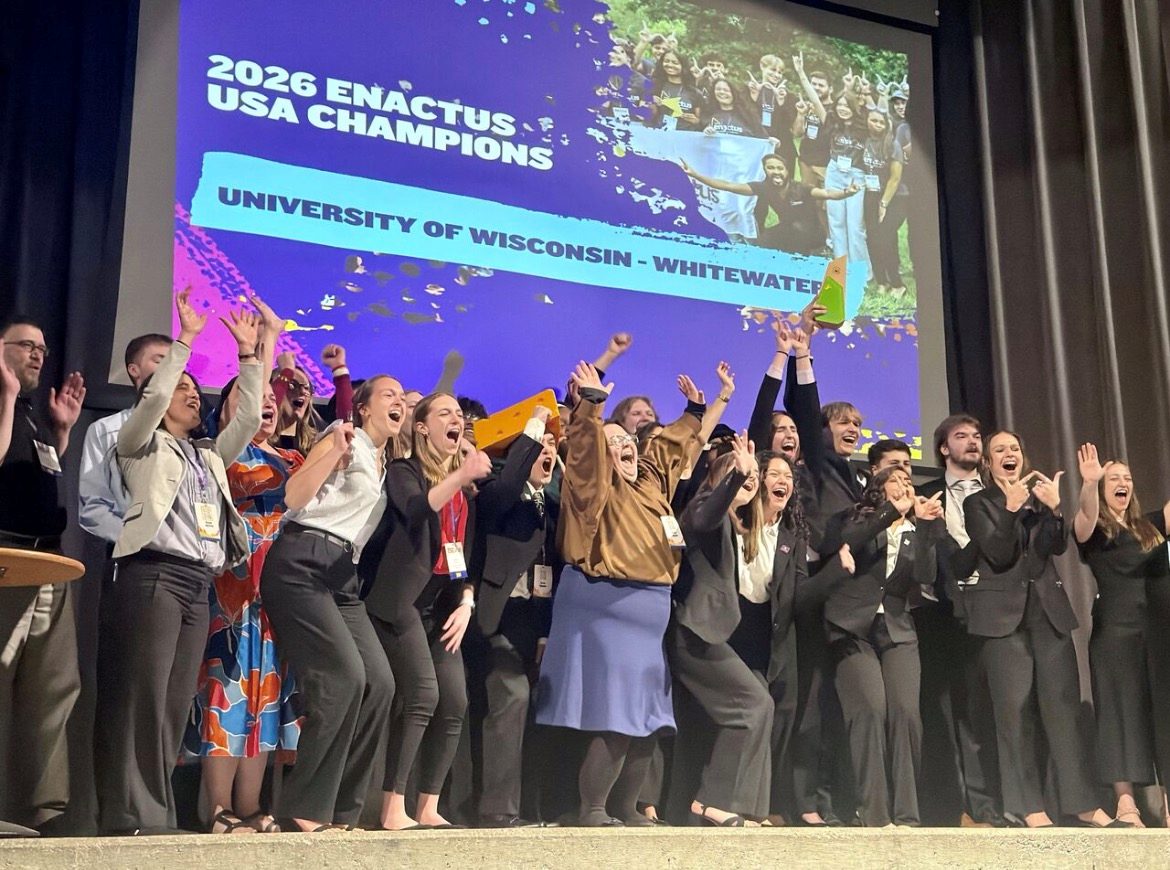 The team cheering on stage under the 2026 Enactus USA Champions slide